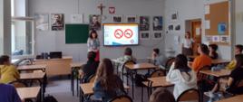 uczniowie w klasie słuchają prelekcji antynikotynowej, na ekranie widoczny znak zakazu palenia