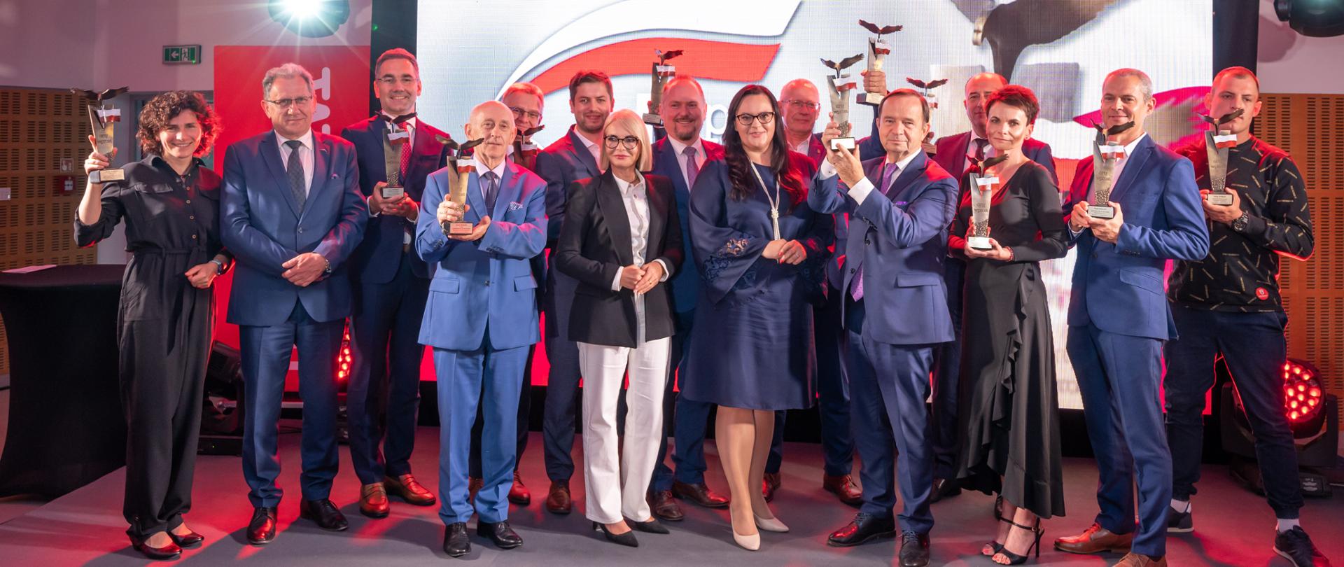 Grupa osób pozuje do zdjęcia ze statuetkami w rękach