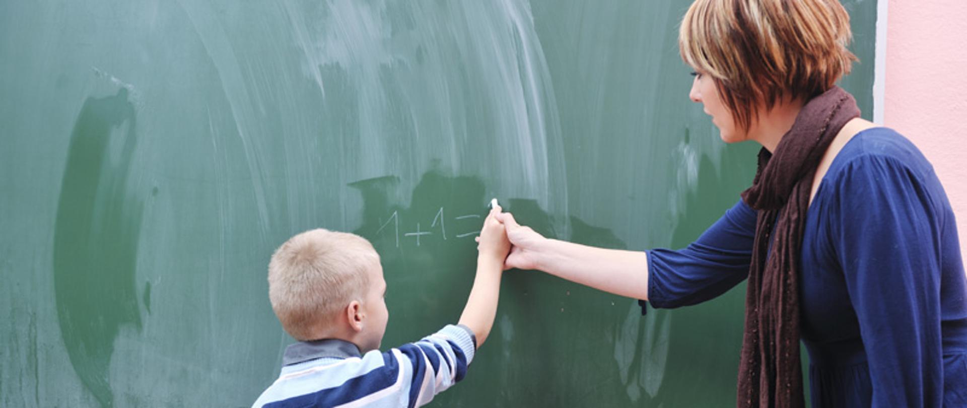 Uczeń przy tablicy z nauczycielką