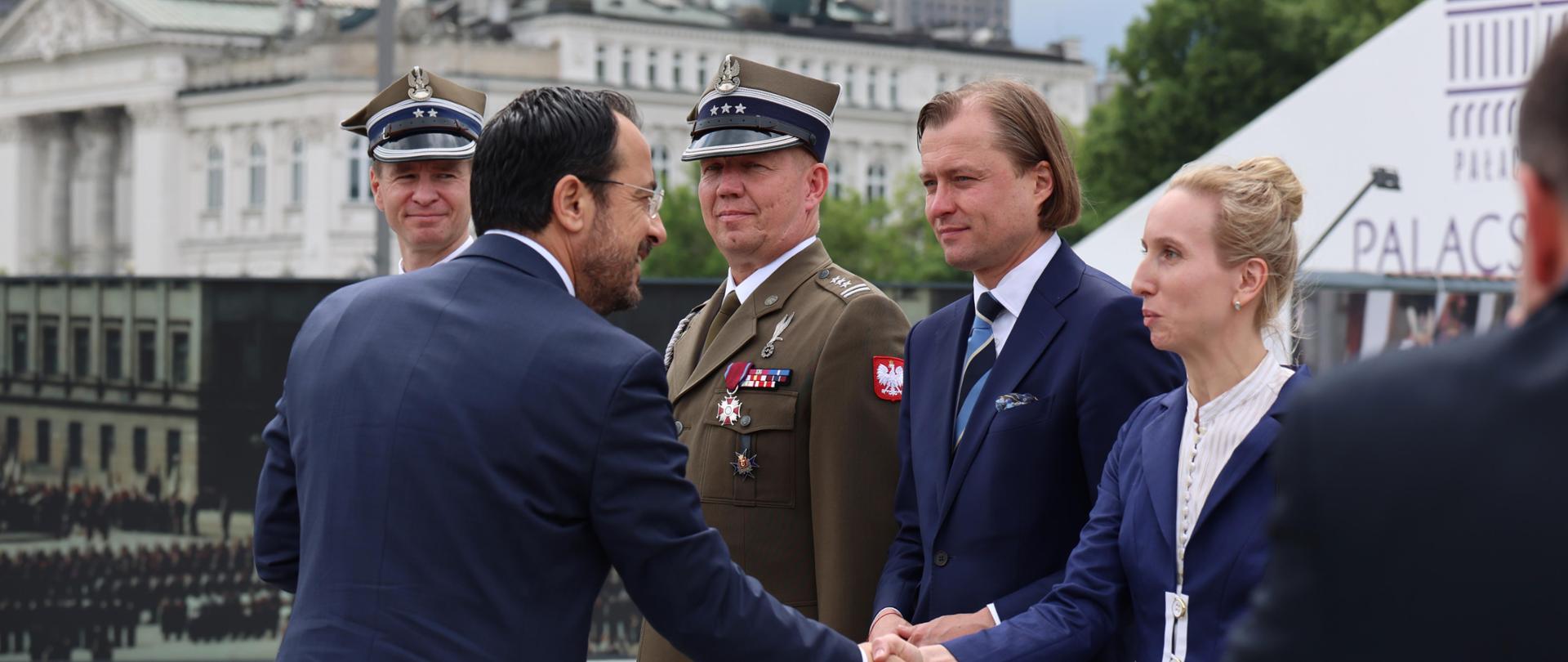 Na zdjęciu grupa ludzi witających się ze sobą 