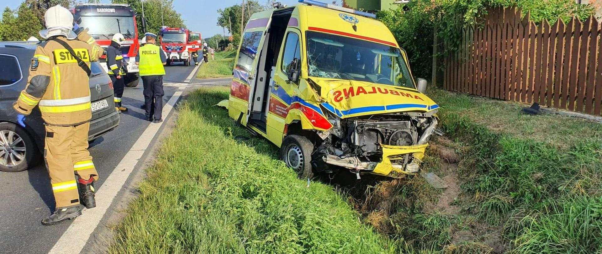 Po prawej jest karetka pogotowia w rowie, po lewej strażacy i policja