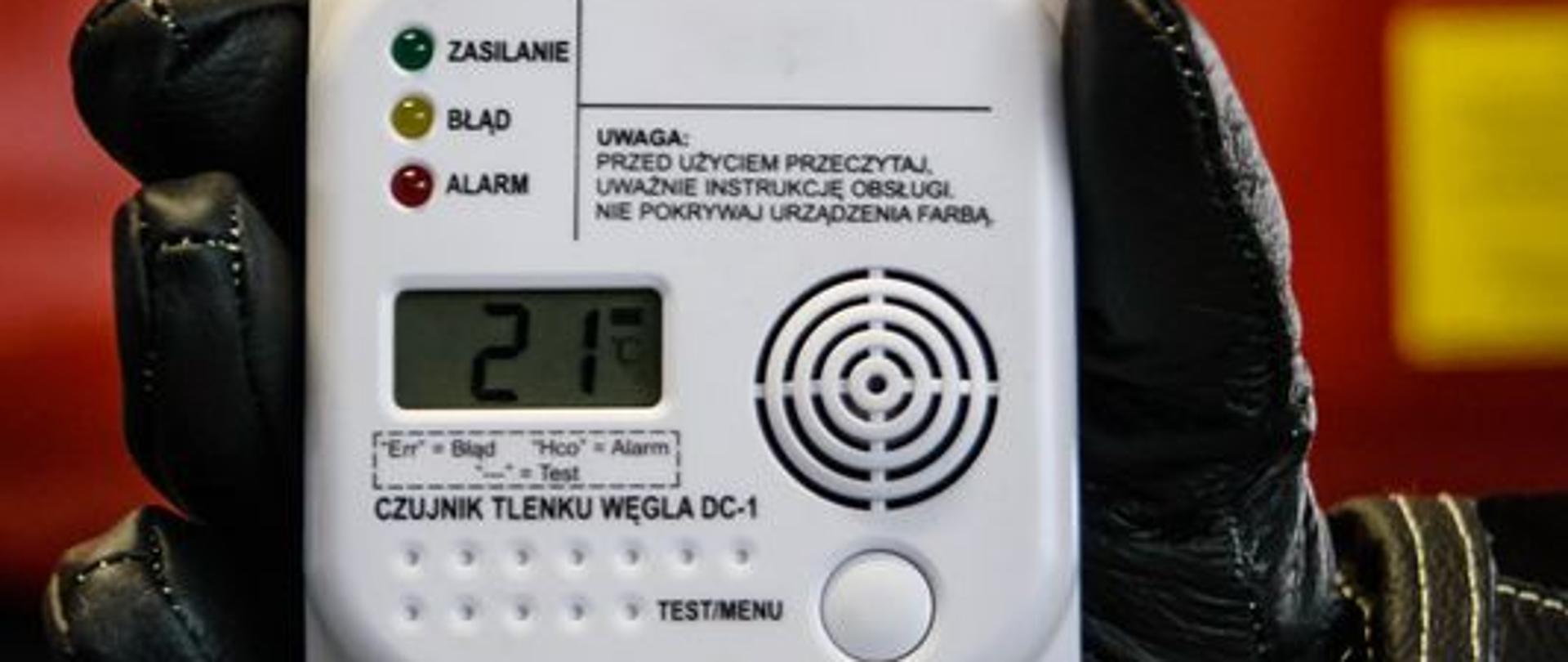 Na zdjęciu czujka tlenku węgla na tle samochodu pożarniczego