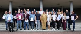 Pamiątkowe zdjęcie grupowe uczestników szkolenia inspektorów ochrony przeciwpożarowej (24 osoby) w towarzystwie Komendanta Centralnej Szkoły PSP, kobiety oraz oficera CS PSP