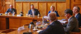 Kilka osób, wśród nich minister Czarnek i wiceminister Machałek, siedzi przy stole i rozmawia.