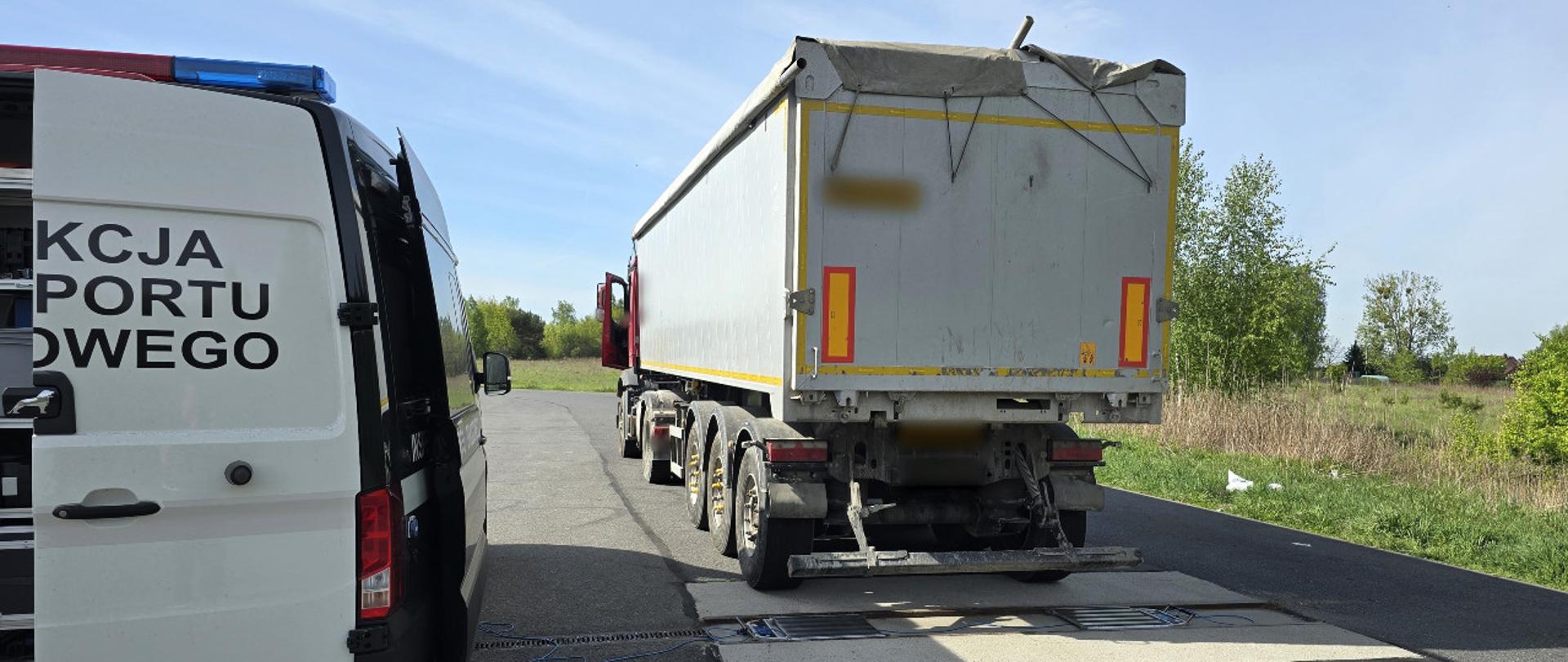 Od lewej: tył oznakowanego furgonu Inspekcji Transportu Drogowego. Obok, za wagami inspekcyjnymi, stoi kontrolowany ciągnik siodłowy z podpiętą naczepą typu wywrotka.