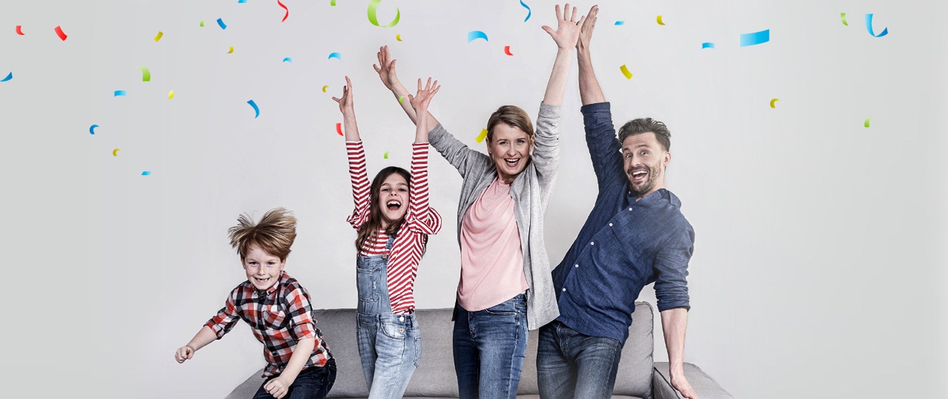Uśmiechnięta czteroosobowa rodzina z uniesionymi rękami