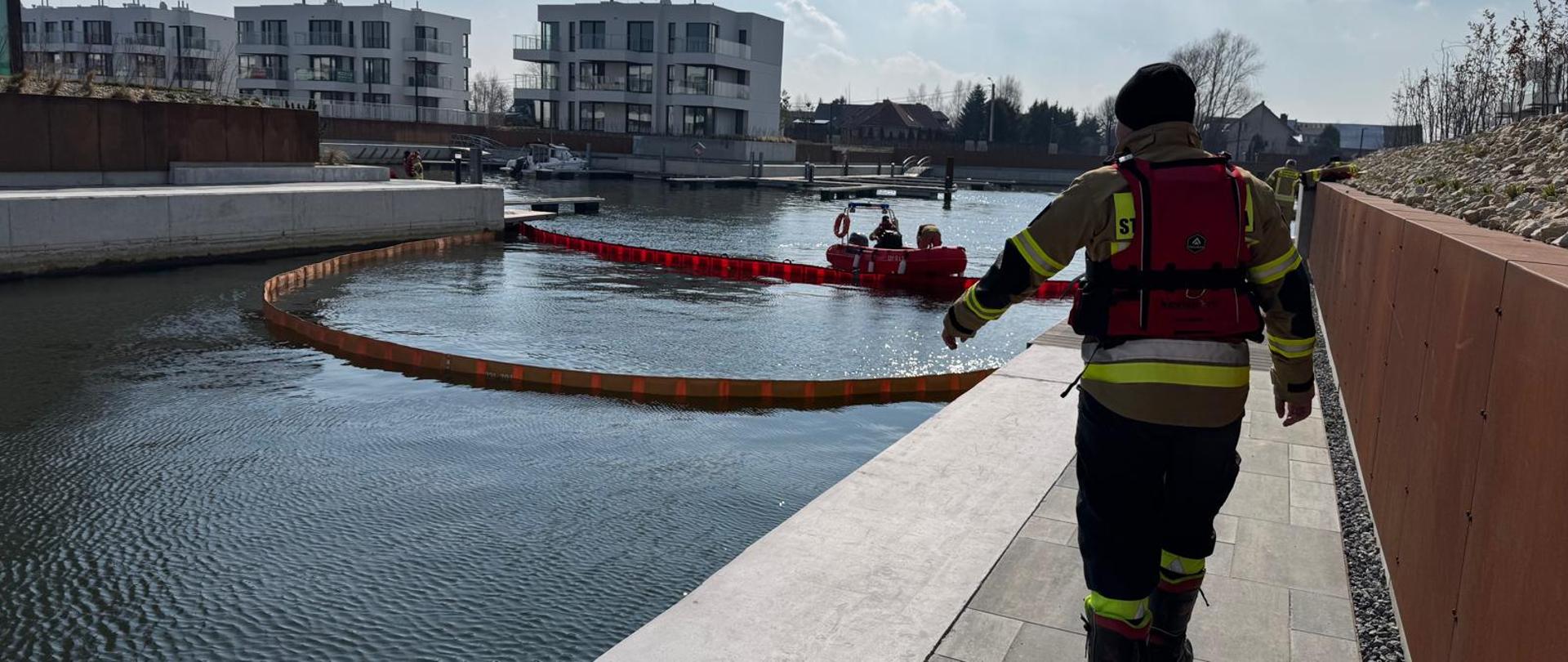 Zdjęcie przedstawia postawioną zaporę, ograniczającą wyciek substancji ropopochodnych.