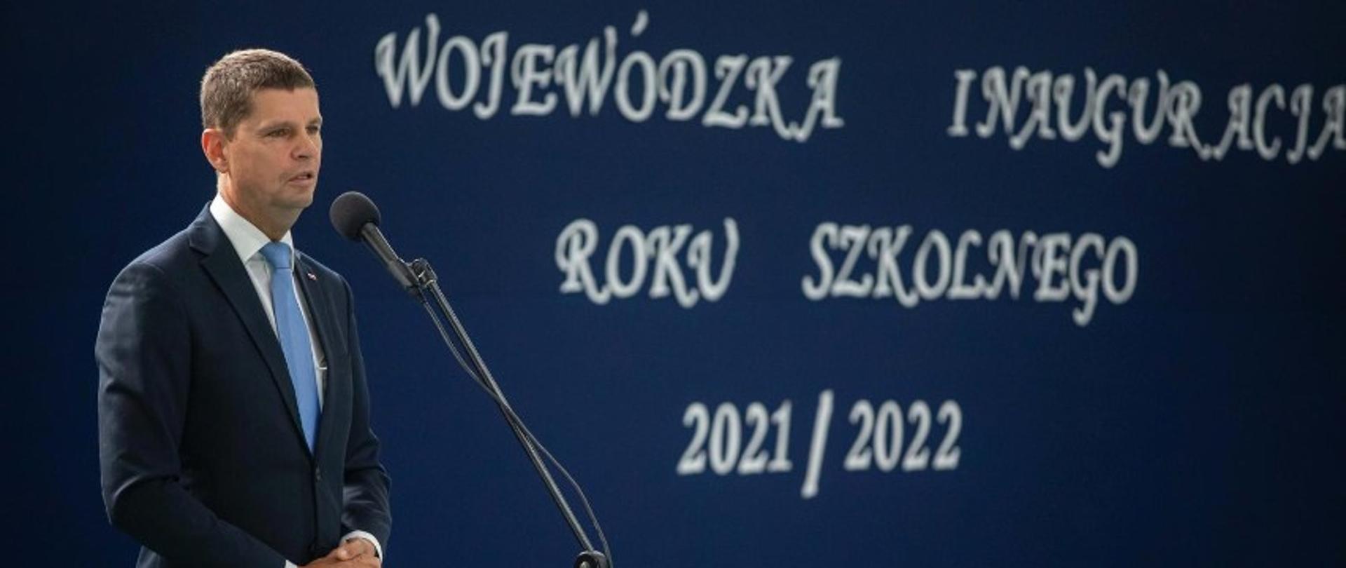 Dariusz Piontkowski, wojewódzka inauguracja roku szkolnego 2021/2022. przemawia do mikrofonu. na sali gimnastycznej w szkole