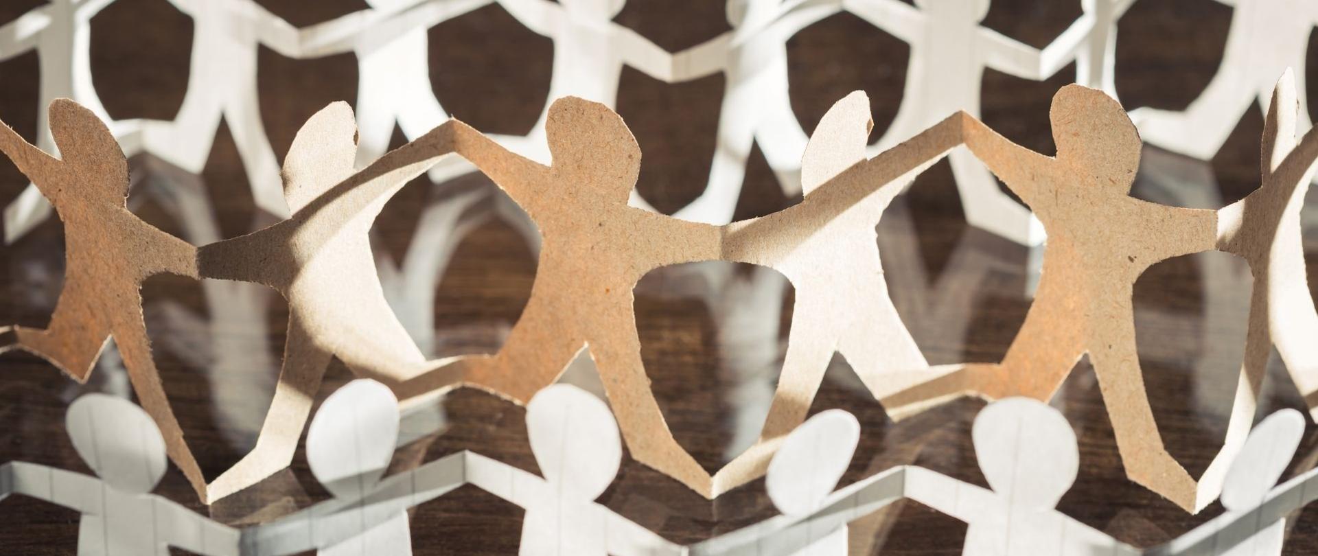 Na zdjęciu znajdują się tekturowe ludziki trzymające się za ręce