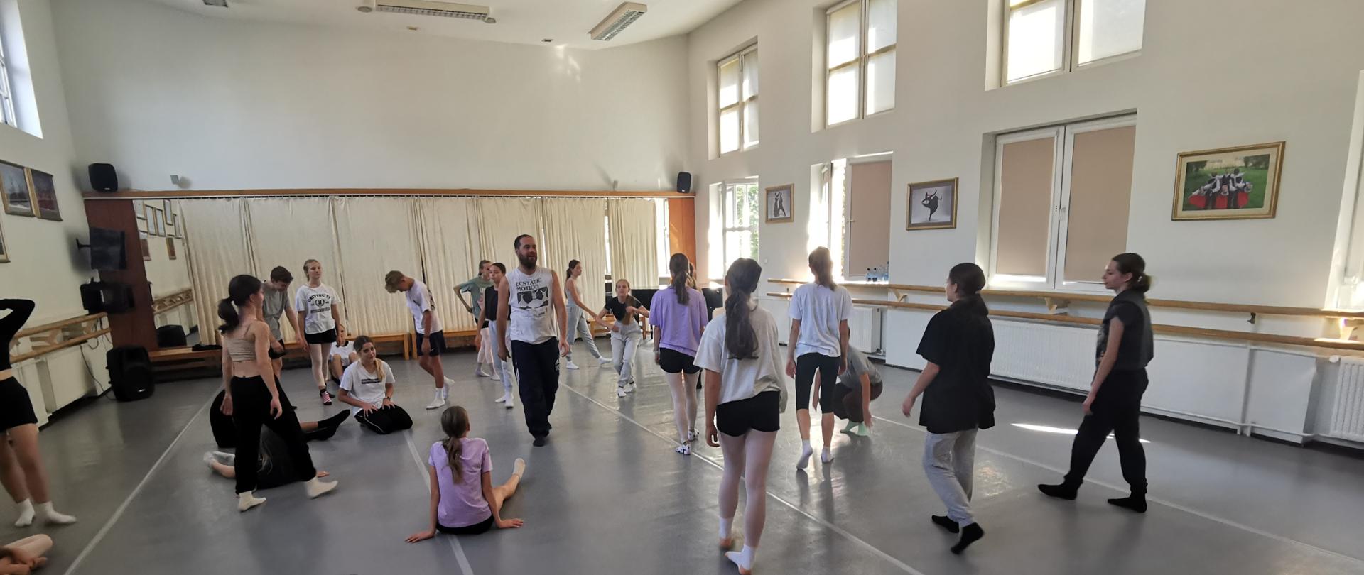 uczniowie siedzą na podłodze sali baletowej warsztaty "Move on togheter"