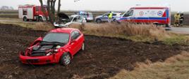 Zdjęcie przedstawia uszkodzone pojazdy w tle pojazdy straży pożarnej, policji i pogotowia. 