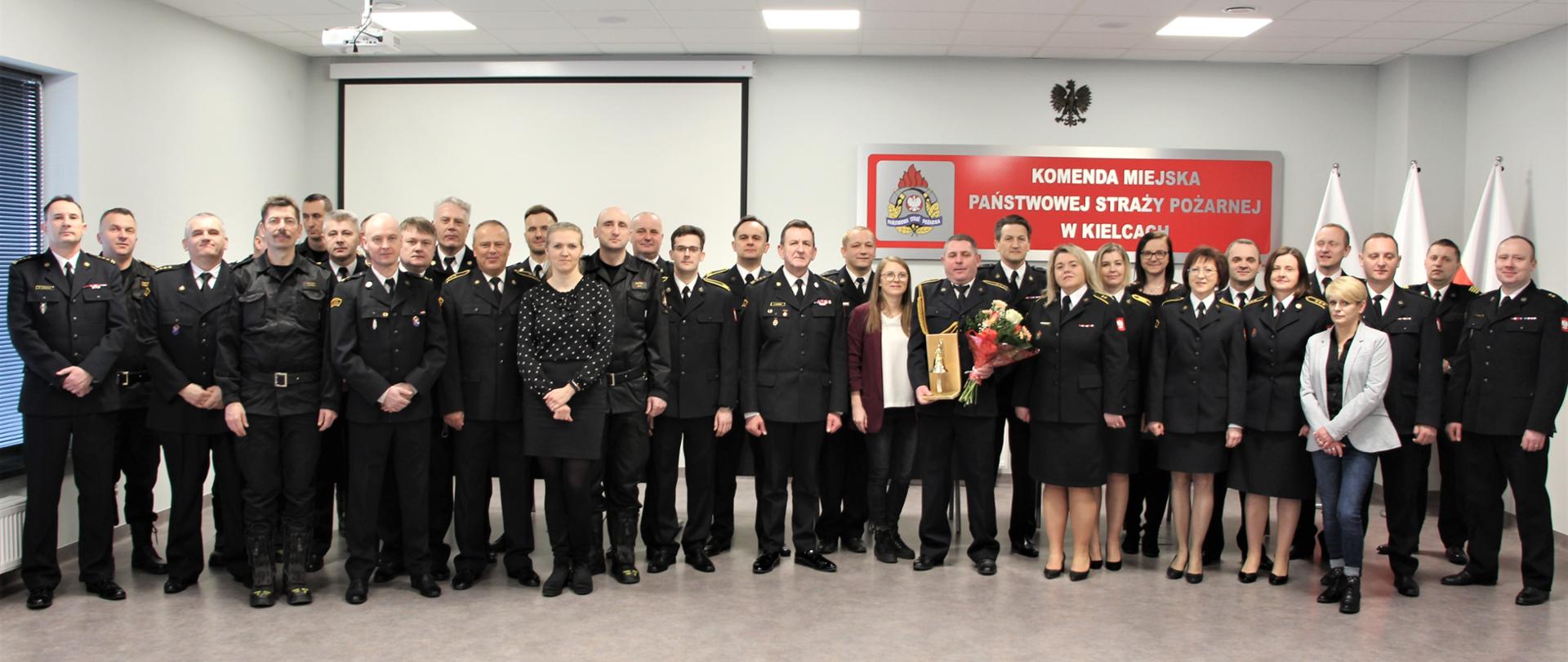 Zdjęcie pamiątkowe: wszyscy obecni na uroczystości funkcjonariusze i pracownicy Komendy Miejskiej Państwowej Straży Pożarnej w Kielcach będący na uroczystości ustawieni do zdjęcia pamiątkowego.