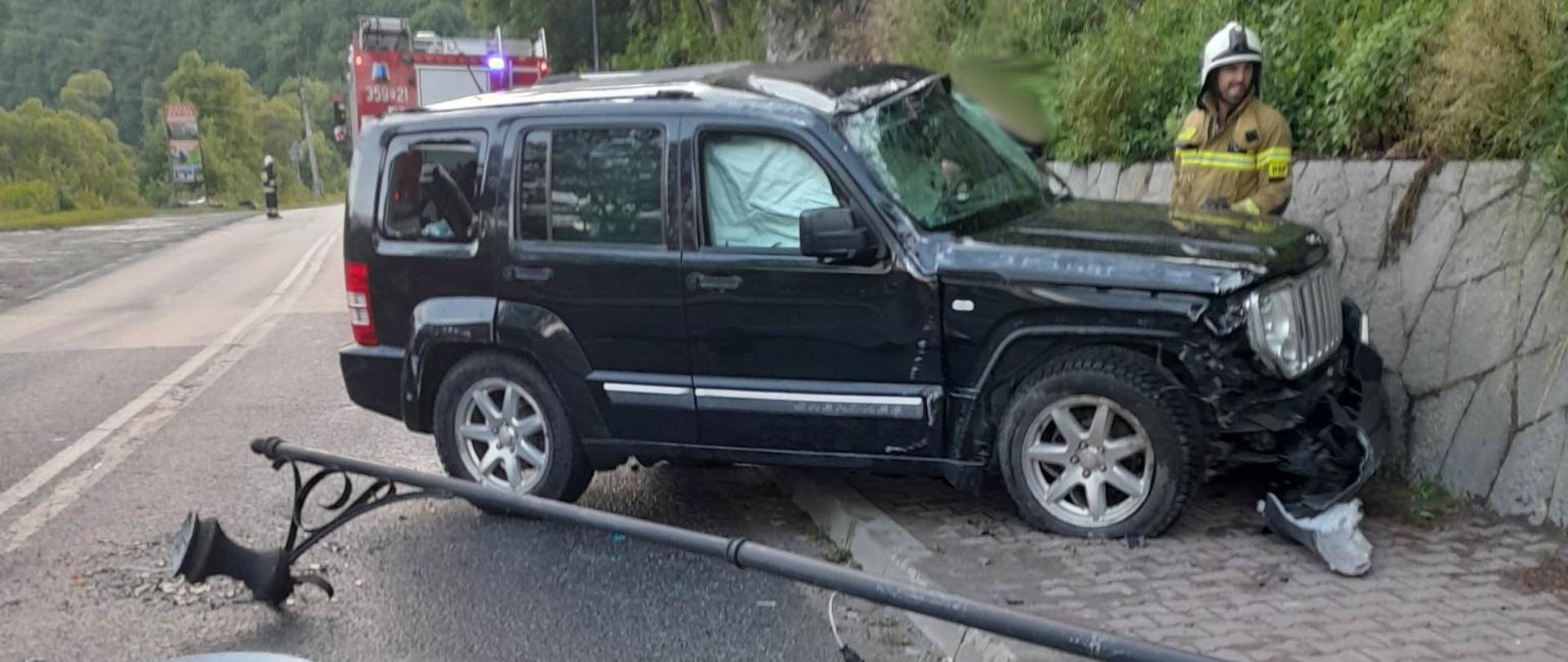 Przewrócona lampa oraz samochód osobowy po uderzeniu