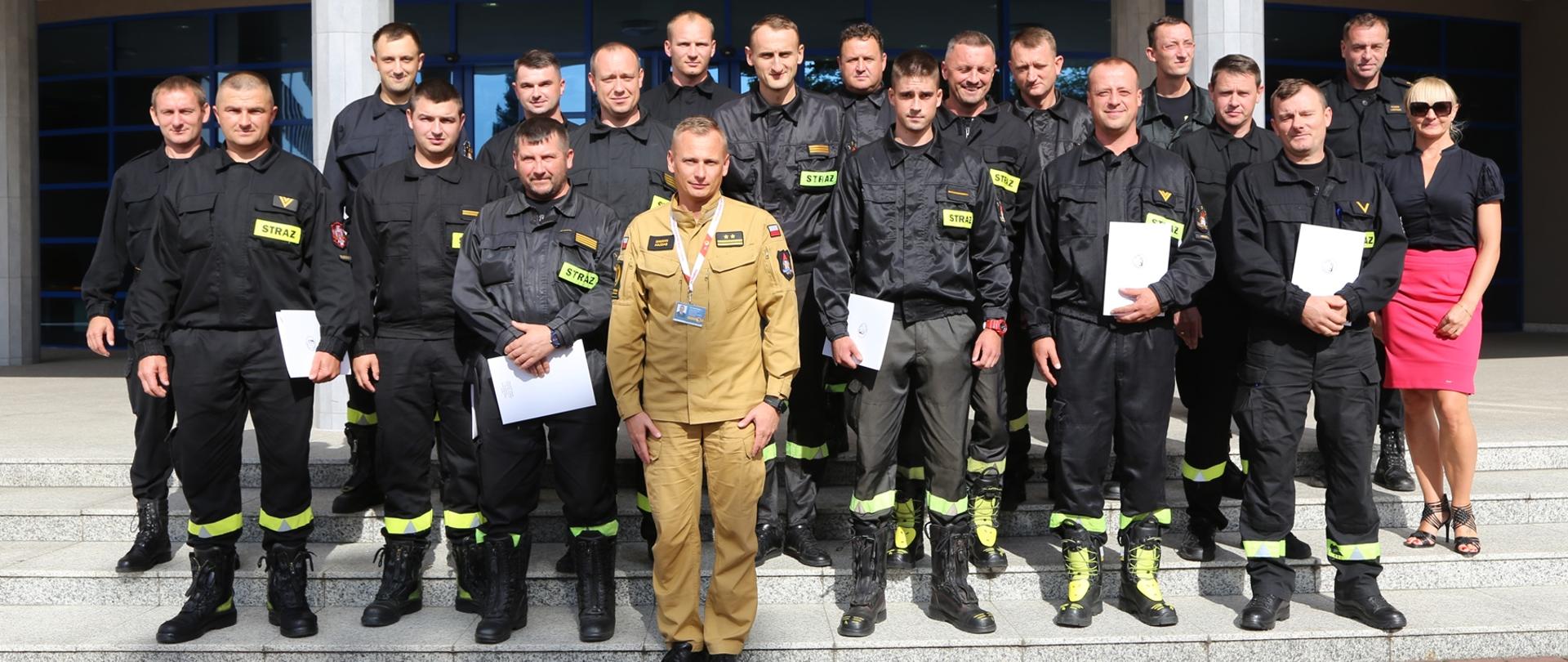 Grupowe zdjęcie uczestników szkolenia (16 osób) w towarzystwie Zastępcy Komendanta Centralnej Szkoły PSP, pracownicy wydziału szkoleń specjalistycznych i współpracy międzynarodowej oraz naczelników wydziału technicznego i wydziału szkoleń specjalistycznych i współpracy międzynarodowej