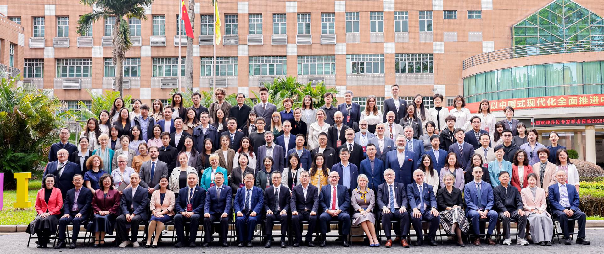 Grupowe zdjęcie uczestników obchodów jubileuszowych przed budynkiem uniwersytetu.