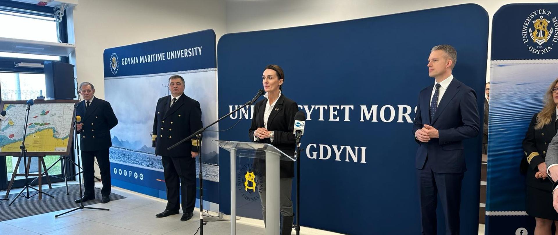 duża sala, kobieta przemawia , w tle baner Uniwersytetu Morskiego w Gdyni