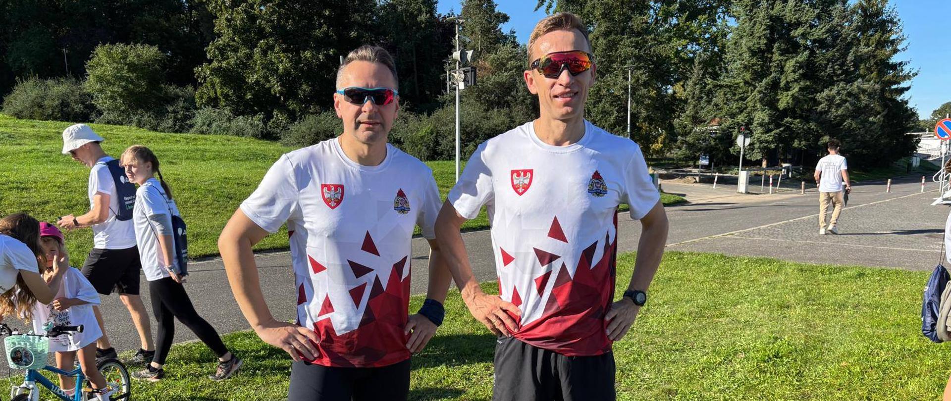 Panowie Komendanci w koszulkach sportowych podczas biegu charytatywnego, na terenie zielonym na poznańskiej Malcie.
