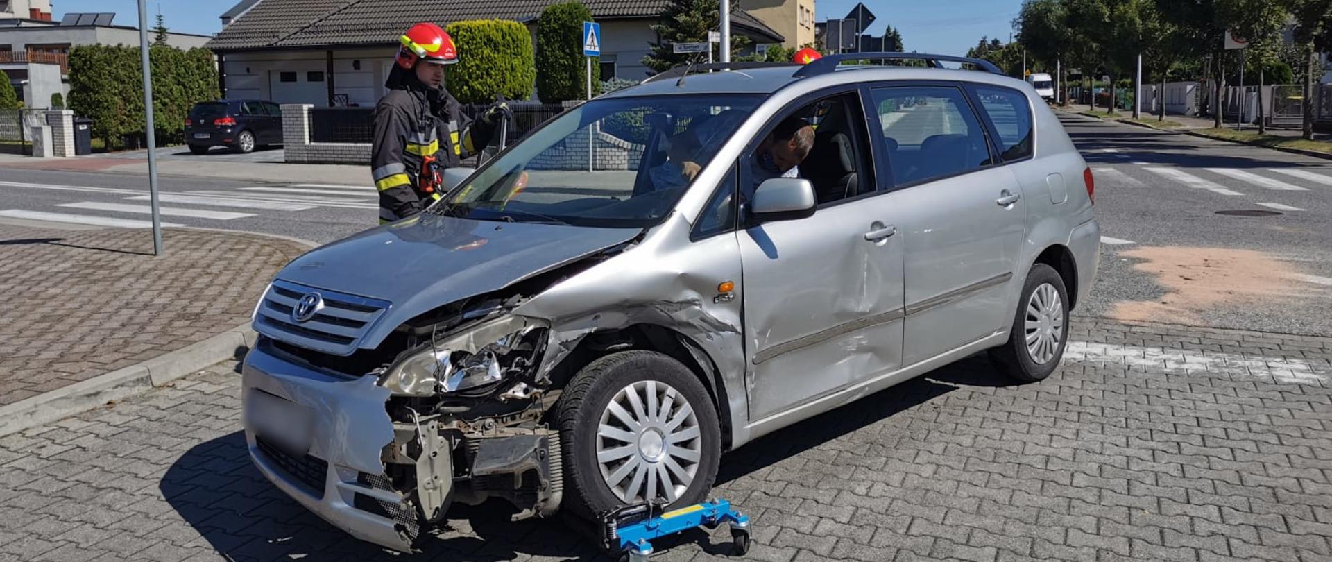 Strażacy prowadzący działania przy rozbitym samochodzie osobowym.