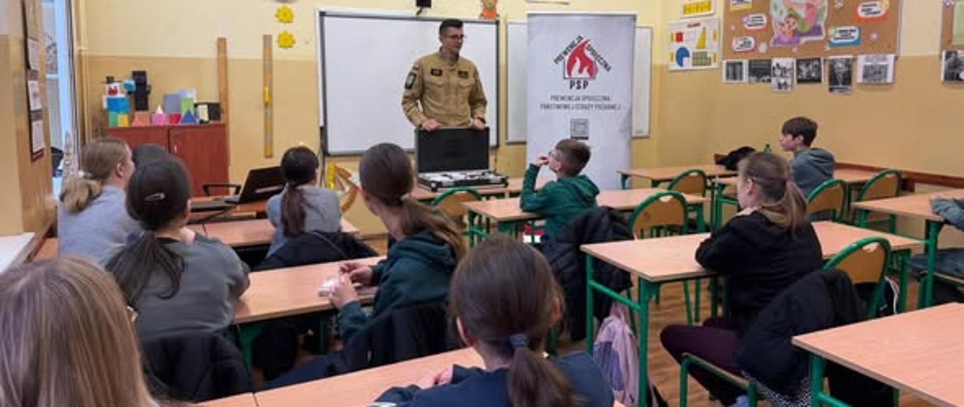Na zdjęciu funkcjonariusz z dziećmi w klasie