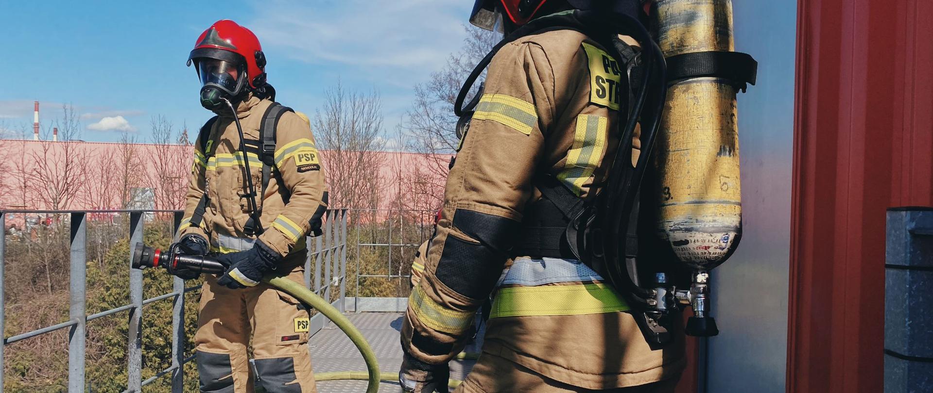 Podsumowanie zdarzeń w dniach 04.04 - 10.04.2022 r. - zdjęcie przedstawia 2 strażaków w pełnym umundurowaniu specjalnym z linią gaśniczą