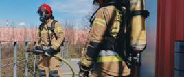Podsumowanie zdarzeń w dniach 04.04 - 10.04.2022 r. - zdjęcie przedstawia 2 strażaków w pełnym umundurowaniu specjalnym z linią gaśniczą