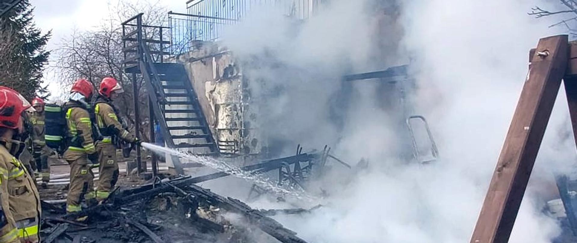 Pożar budynku, na zdjęciu ratownicy, działania gaśnicze prowadzone z kosza drabiny, 