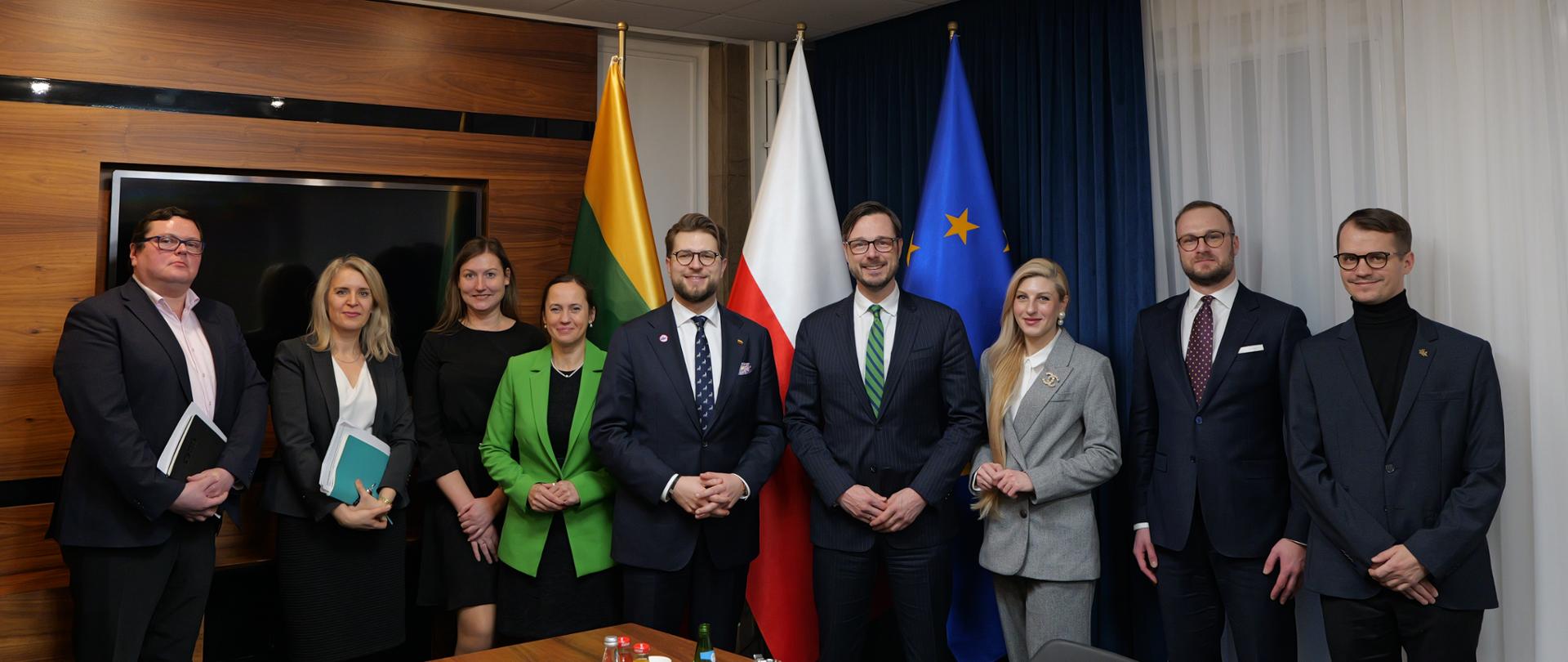 Family photo. Przedstawiciele delegacji litewskiej z ministrem gospodarki i innowacji Litwy, Lukasem Savickasem na czele oraz przedstawiciele Ministerstwa Aktywów Państwowych z ministrem Jakubem Jaworowskim na czele. W tle flagi.