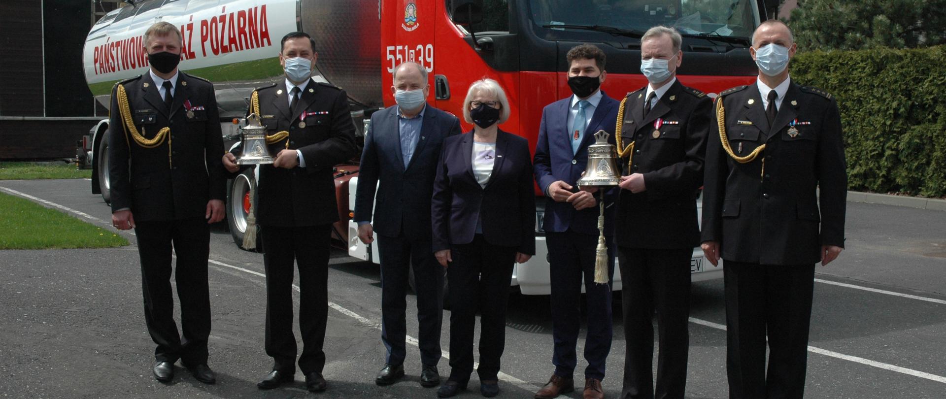 Kierownictwo KP PSP w Stalowej Woli z Senator RP Janiną Sagatowską, Januszem Zarzecznym – starostą stalowowolskim, Lucjuszem Nadbereżnym – Prezydentem Miasta Stalowej Woli na tle samochodu pożarniczego. 