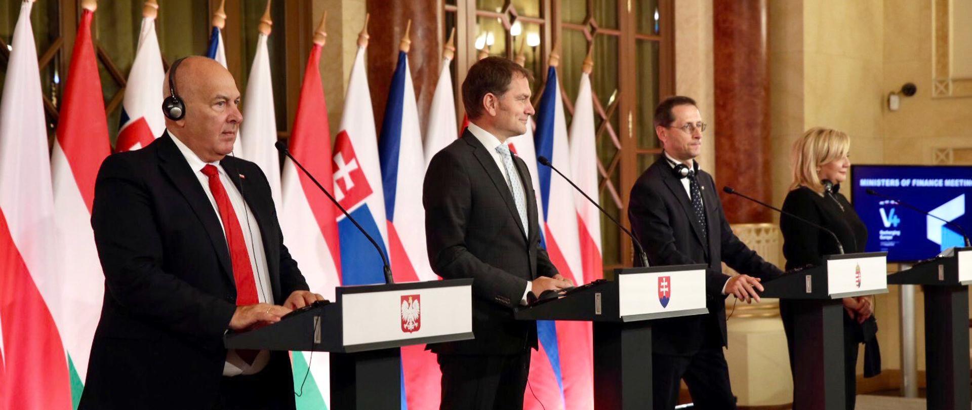 Uczestnicy spotkania przy mównicach, cztery osoby, na pierwszym planie minister finansów Tadeusz Kościński.