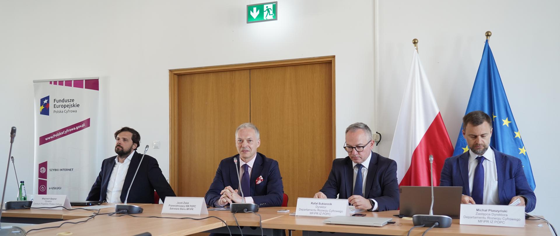 wiceminister Jacek Żalek wśród prowadzących komitet, za nimi flagi Polski i UE