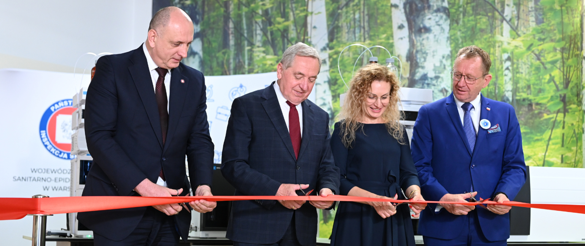Kobieta i trzej mężczyźni przecinają wstęgę.