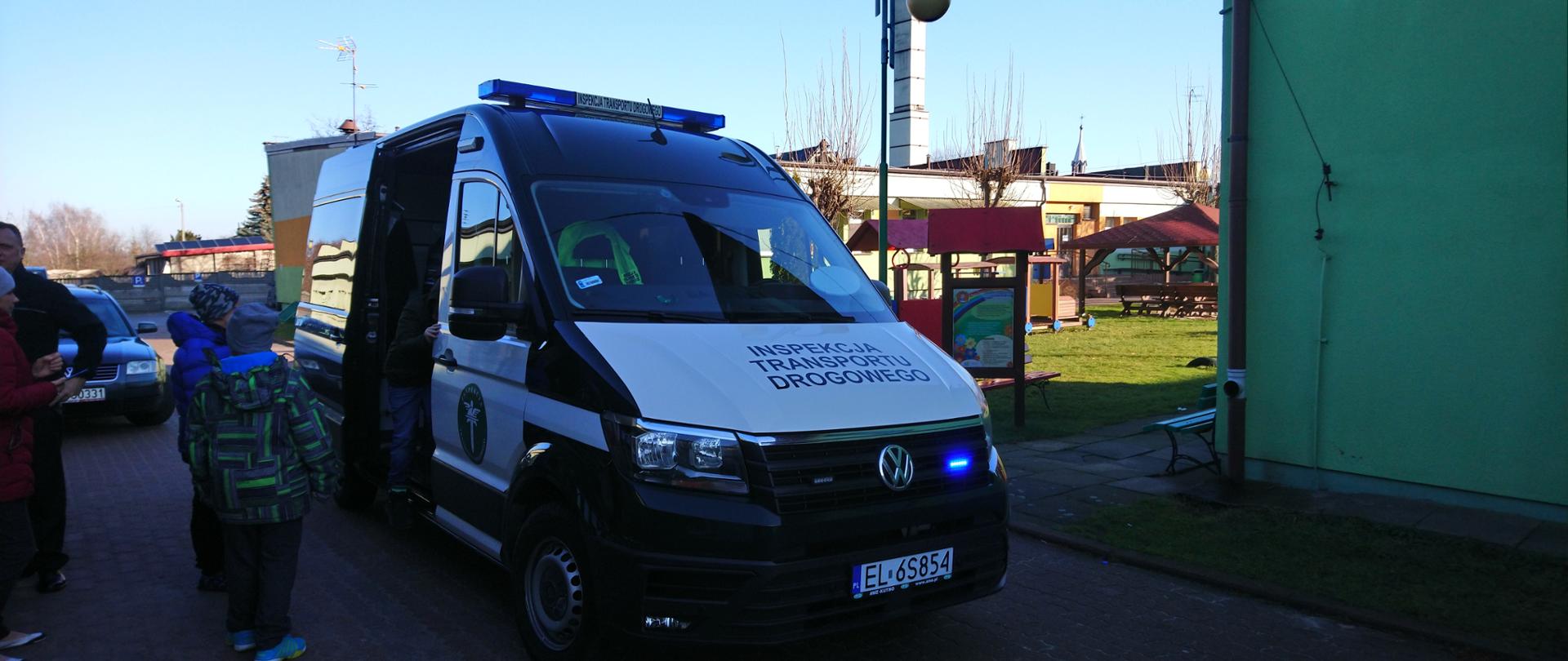 Dzieci przy radiowozie Inspekcji Transportu Drogowego na parkingu przy szkole