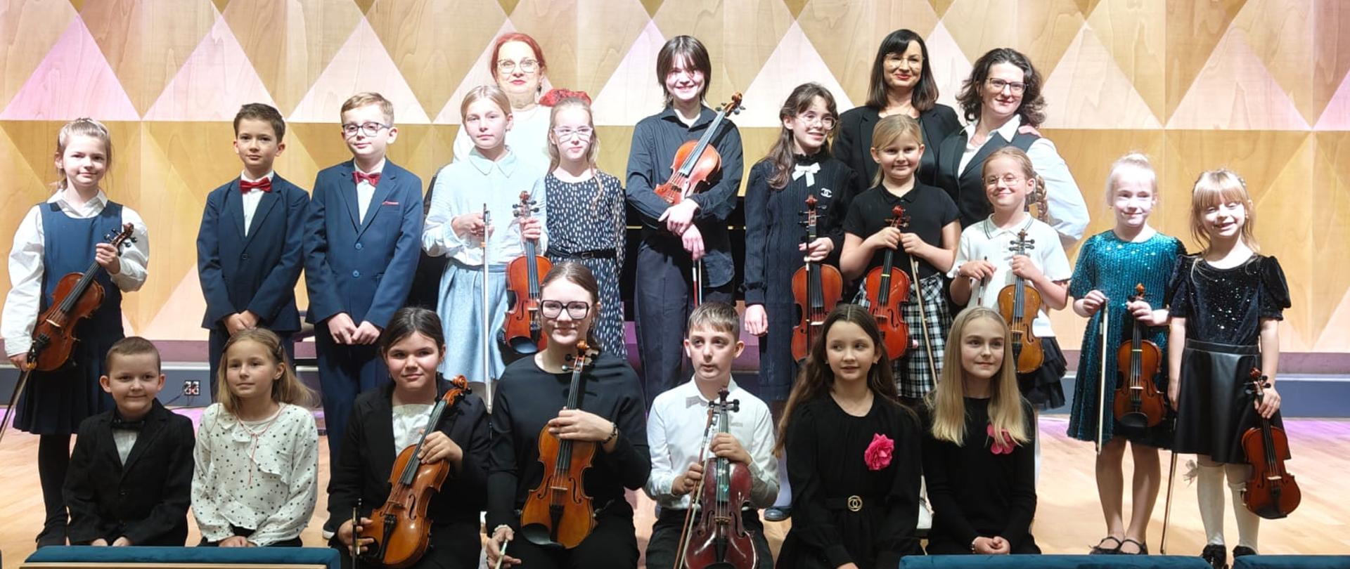 grupa uczniów na tle sali koncertowej PSM