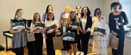 Zdjęcie grupowe uczestników II grupy konkursowej. Uczennice trzymają dyplomy. Za nimi stoją nauczyciele
