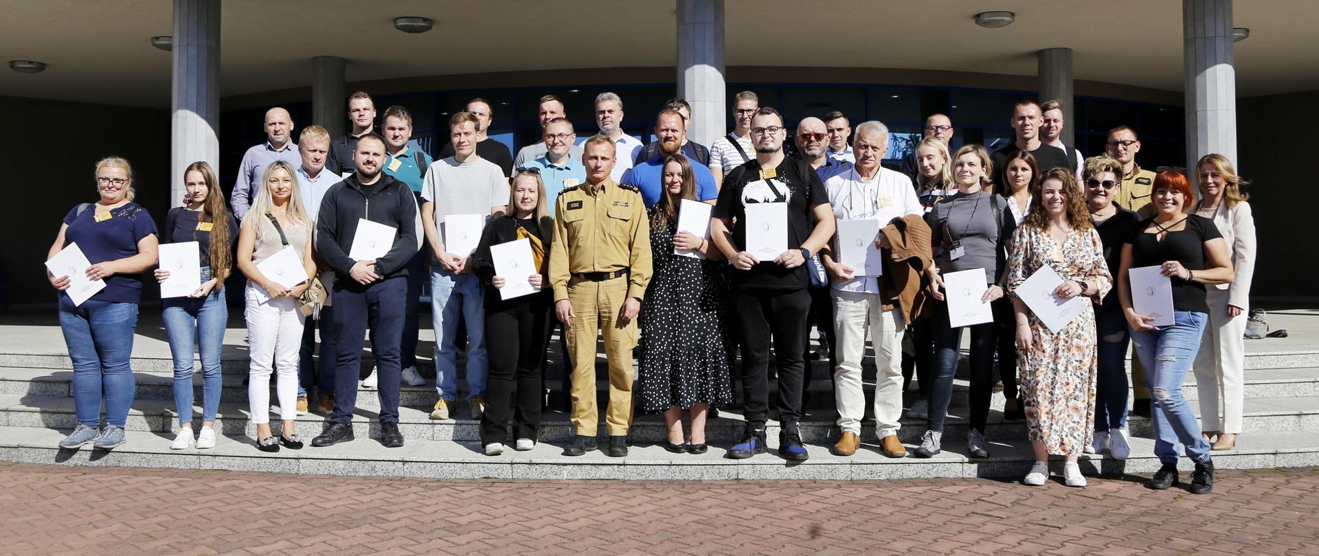 Grupowe zdjęcie uczestników szkolenia (31 osób) w towarzystwie Zastępcy Komendanta Centralnej Szkoły PSP, funkcjonariusza CS PSP oraz kobiety