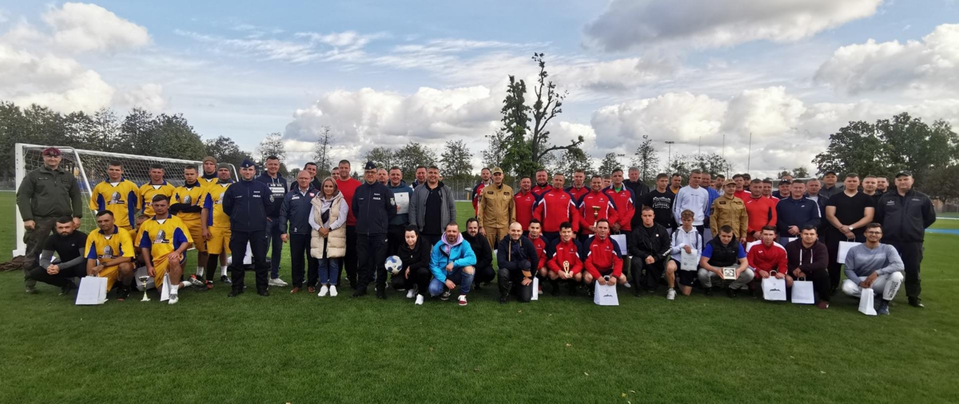 Na zielonym boisku zawodnicy oraz goście pozują do zdjęcia.