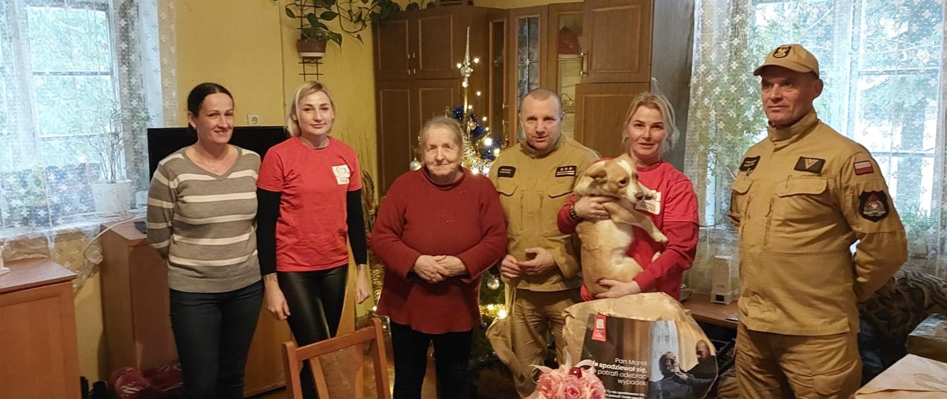 Strażacy i wolontariusze szlachetnej paczki w mieszkaniu z prezentami.