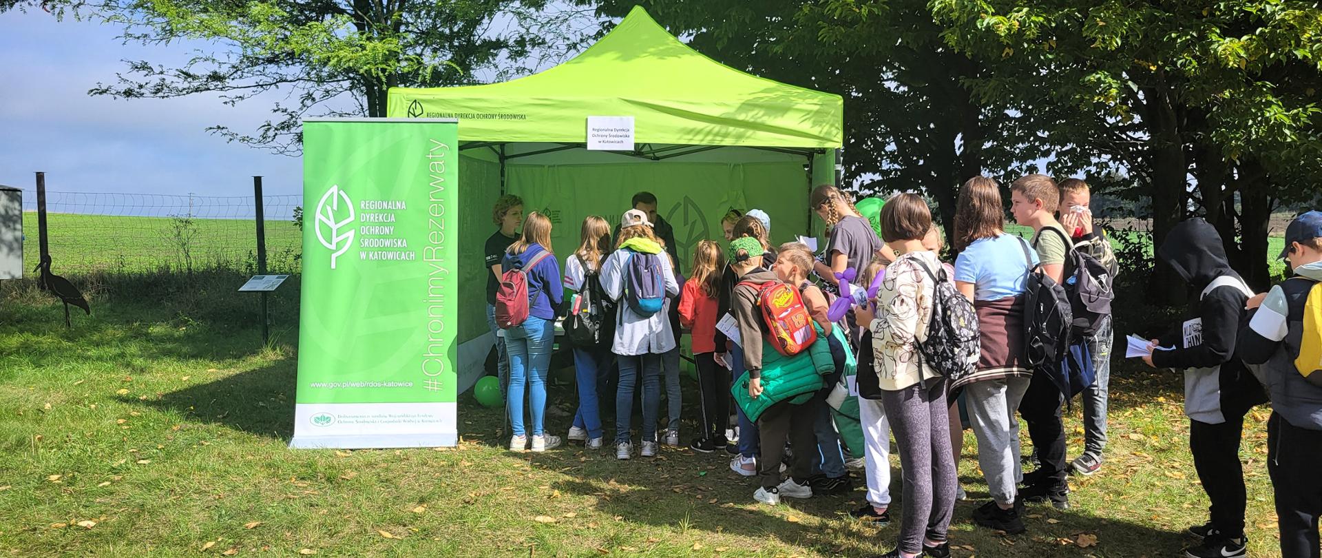 Grupa dzieci stojąca w kolejce do namiotu informacyjnego