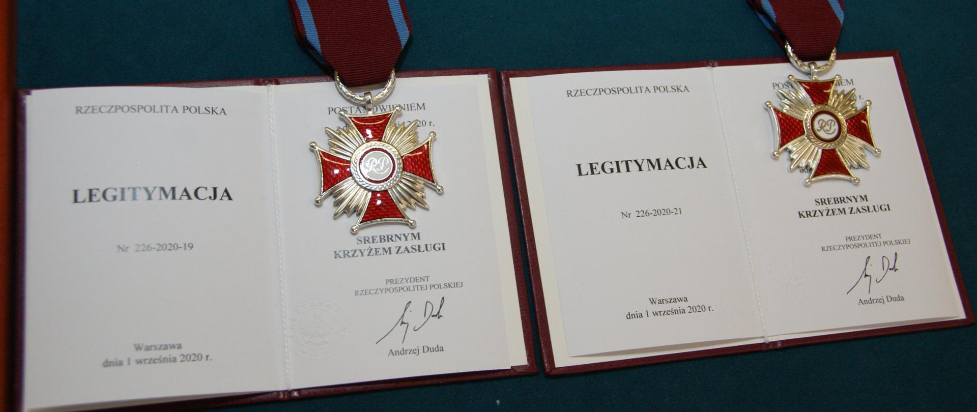 Dwa odznaczenia „Srebrny Krzyż Zasługi” ułożone na otwartych legitymacjach