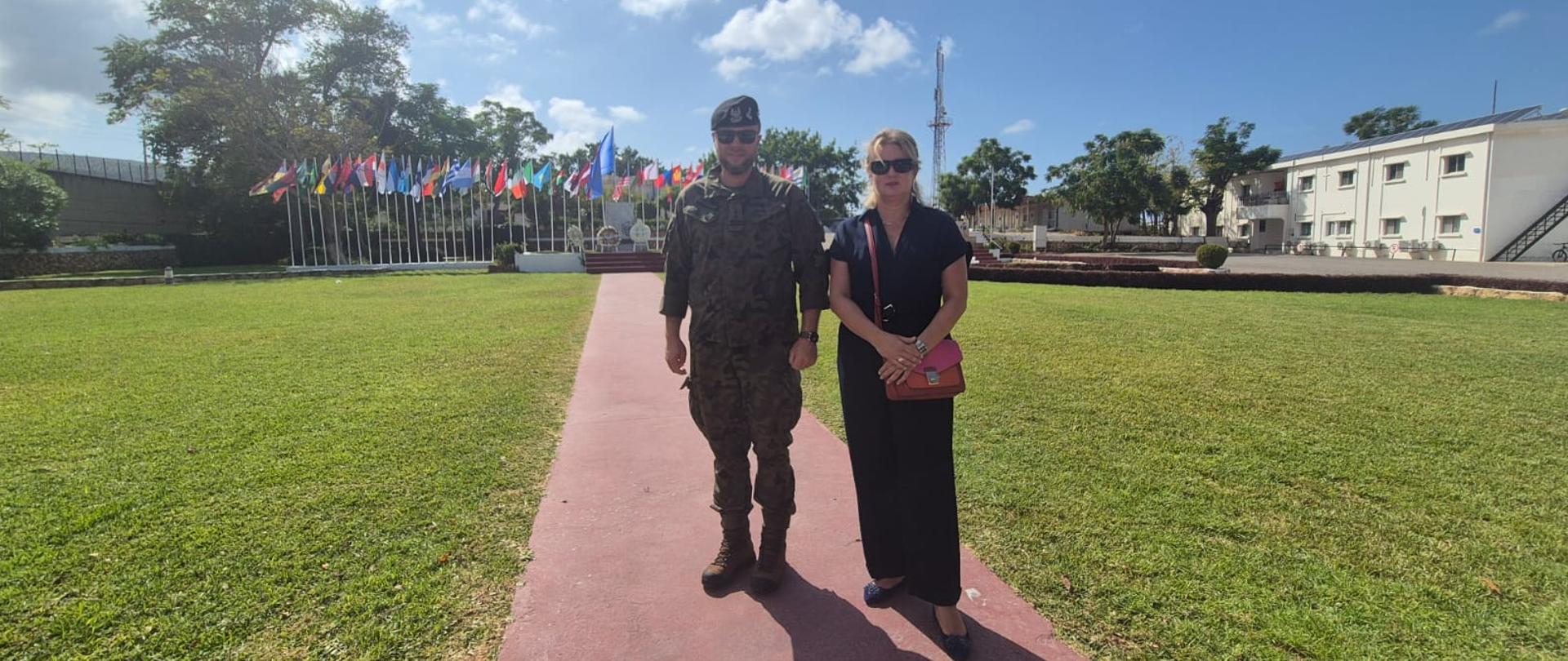 Ambasador A. Bukowska McCabe oraz Attaché Obrony P. Pochwatka pozują na tle flag w bazie misji UNIFIL w Naqura