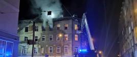 Na zdjęciu drabina mechaniczna w tle dym wychodzący z okien mieszkania w kamienicy
