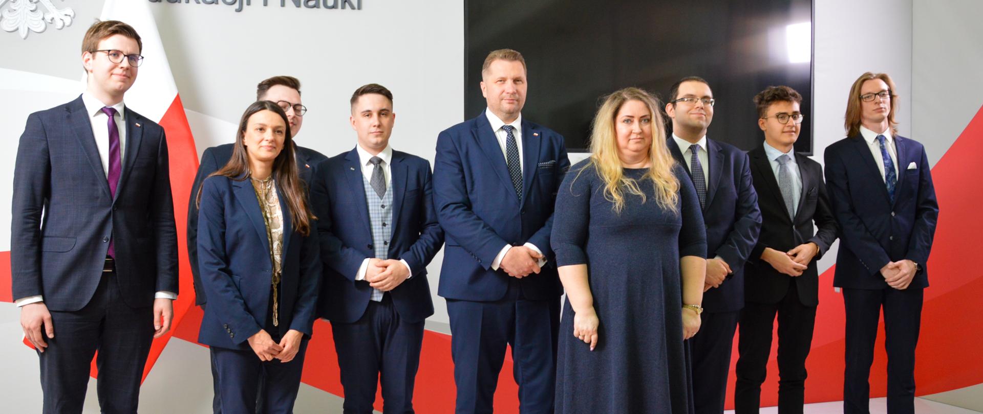 uczestnicy spotkania wraz z ministrem Czarnkiem pozuja do wspólnego zdjęcia na tle ściany z napisem ministerstwo edukacji i nauki