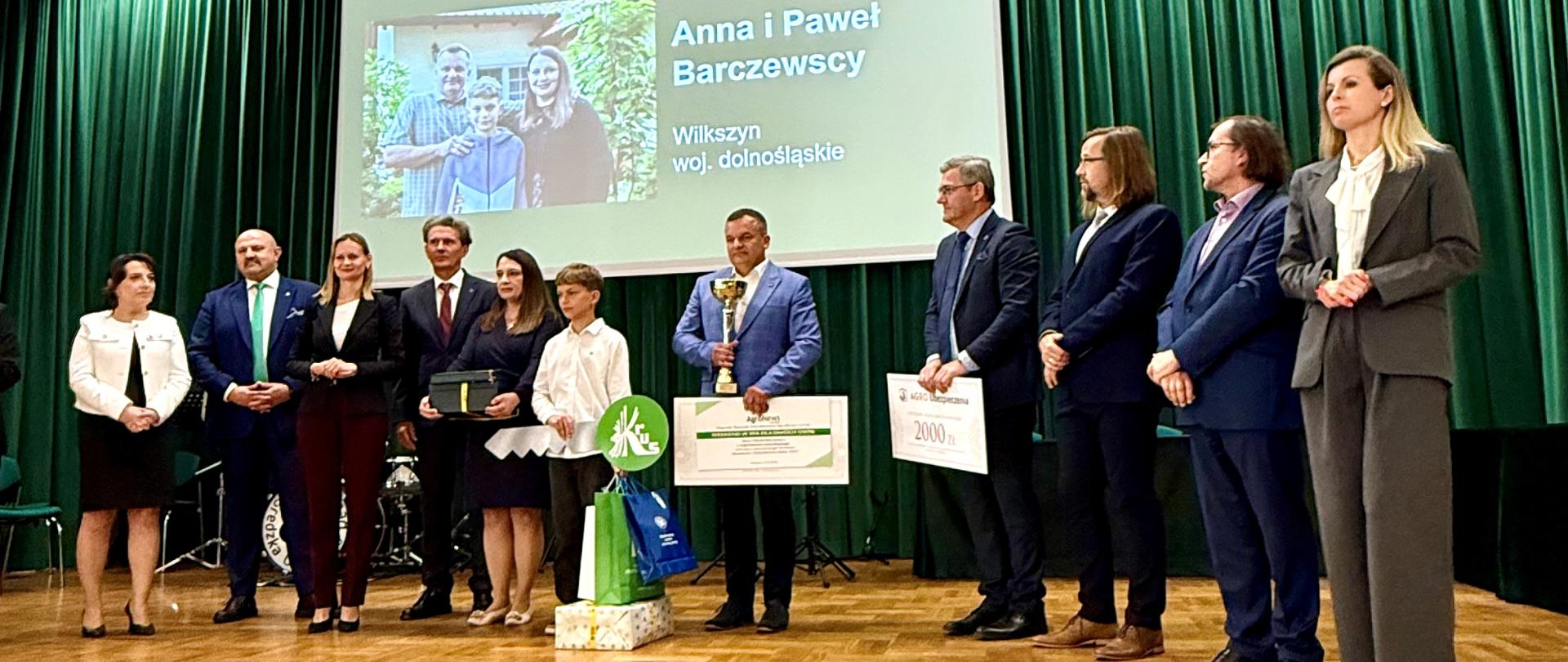 Na scenie stoją w rzędzie organizatorzy wraz ze zwycięzcami