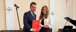 Poseł Przemysław Witek oraz nagrodzony uczeń na scenie w sali koncertowej podczas Uroczystego Koncertu Absolwentów w Państwowej Szkole Muzycznej I st. w Lublińcu