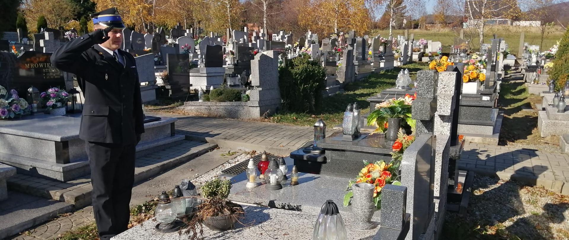 Komendant Powiatowy PSP w Żywcu oddaje honor przed grobem zmarłego.