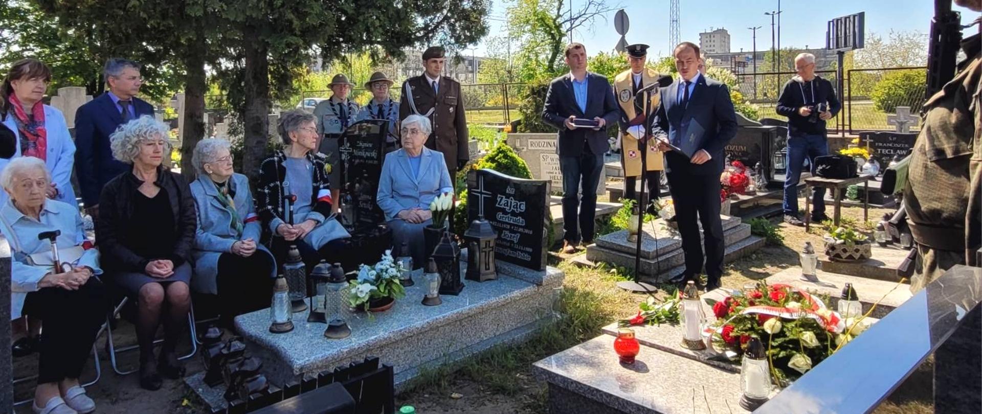 
Grupa ludzi stojąca na cmentarzu
