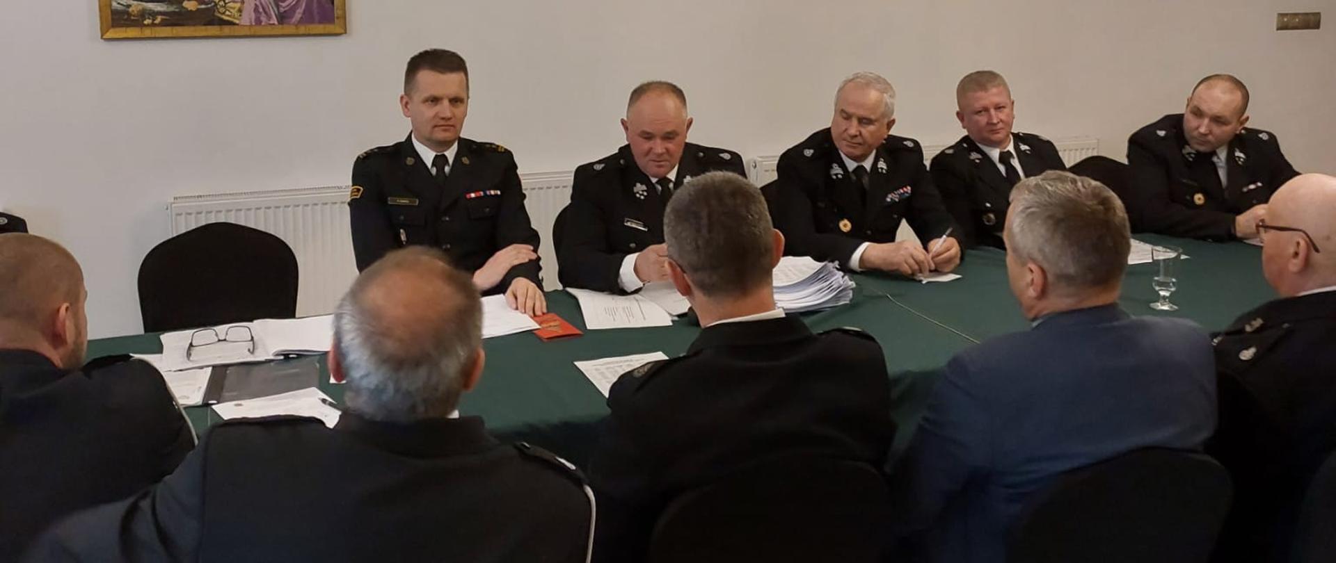 Zdjęcie przedstawiające siedzących przy stole druhów prezesów OSP z terenu powiatu szydłowieckiego wraz z Komendantem Powiatowym PSP podczas Posiedzenie Zarządu Oddziału Powiatowego ZOSP RP w Szydłowcu