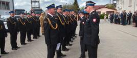 Uroczysta zbiórka strażacka na placu wewnętrznym Komendy Powiatowej – strażacy w galowych mundurach stoją w szeregu podczas wręczenia wyróżnienia awansów na wyższe stopnie służbowe.