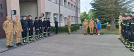 Uroczysta zbiórka strażaków przed komenda, po lewej i prawej stronie stoją w szeregu strażacy.