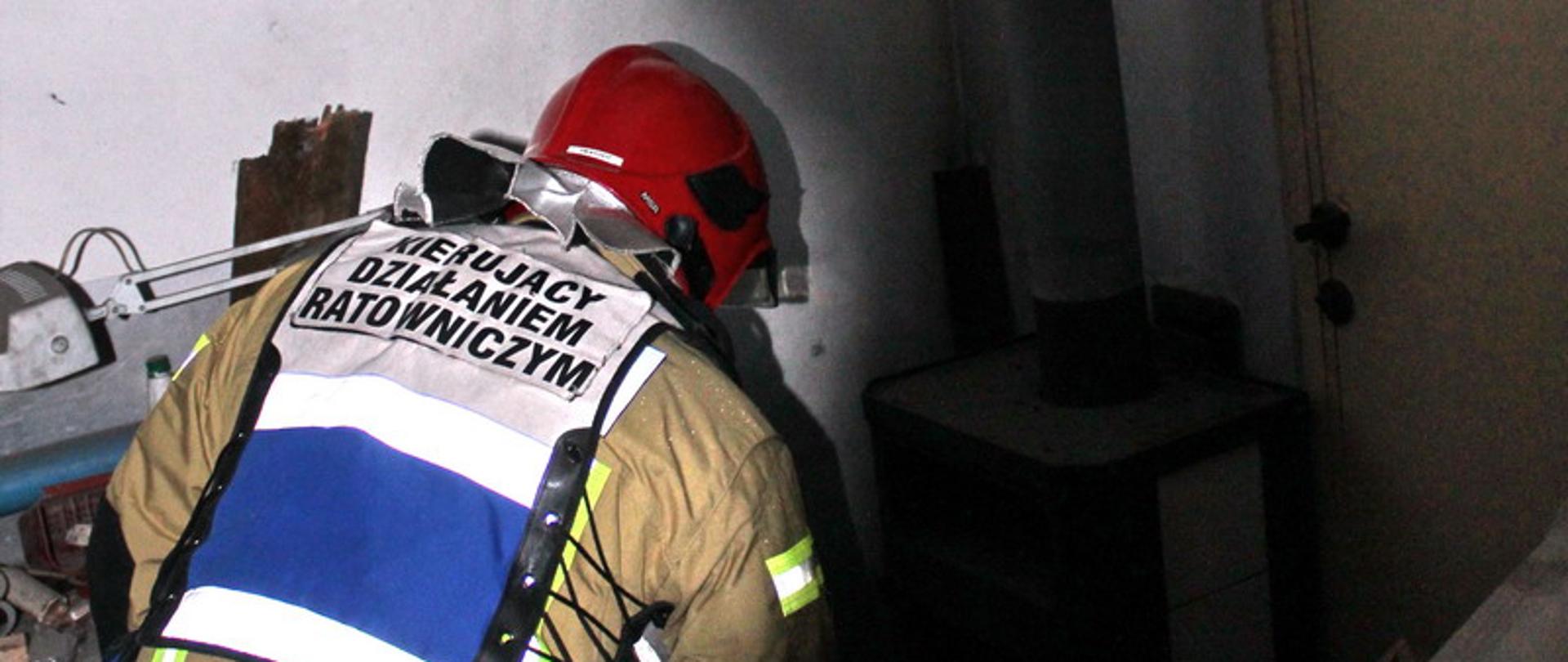 Strażak sprawdza piec znajdujący się w pomieszczeniu, w którym doszło do wybuchu